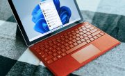 Red Surface laptop on a checkered bed by a window