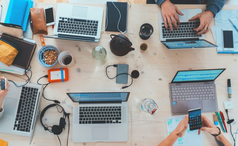 people sitting down near table with assorted laptop computers