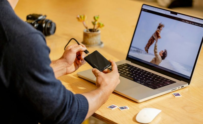 A man sitting at a table with a laptop and cell phone