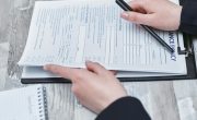 Free Close-up of hands analyzing insurance policy paperwork with pen on table. Stock Photo