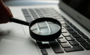 magnifying glass near gray laptop computer