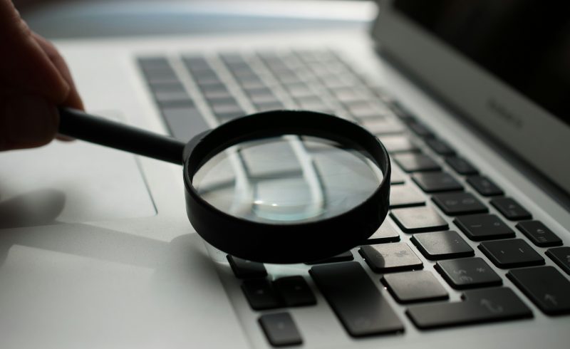 magnifying glass near gray laptop computer